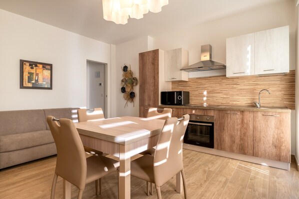 A modern kitchen with a dining area, wooden cabinets, a microwave, and a built-in oven.