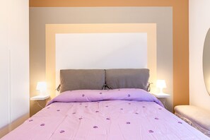 A bedroom with a bed, two bedside lamps, a nightstand, and a mirror.