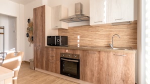 Una cocina moderna con armarios de madera, horno empotrado, microondas y un lavaplatos de acero inoxidable.