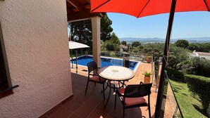 A covered patio with a pool, outdoor seating, and a view of the landscape.