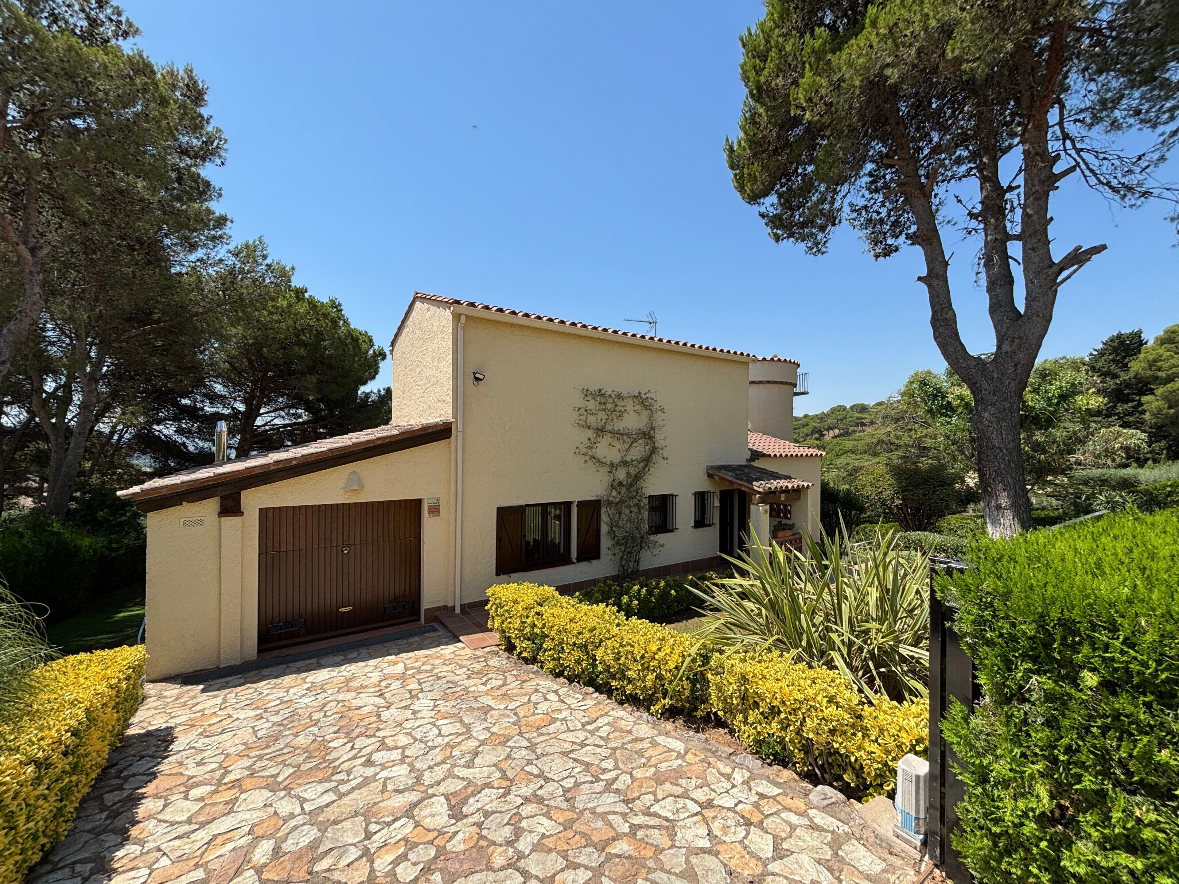 A house with a stone-paved entrance, a garage, and a garden with various plants.