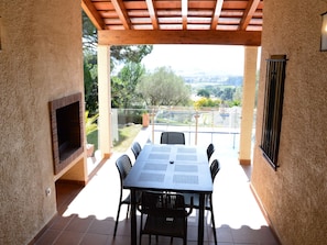Une terrasse extérieure avec une table et des chaises, un téléviseur et une vue sur le paysage.