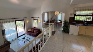 A spacious living area with a sofa, a dining table, and a kitchen area with a sink and cabinets.