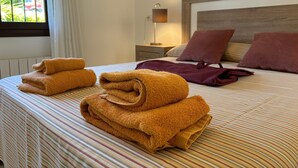 A neatly made bed with striped bedding, a headboard, and a window with curtains.