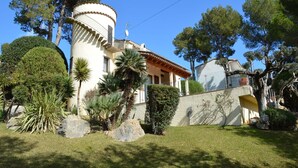 A building with a circular tower, surrounded by well-maintained gardens and trees.