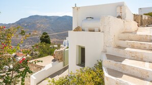 Un bâtiment blanc avec un mur en pierre, une fenêtre et une vue sur les montagnes.