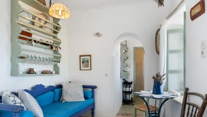 Une pièce avec un canapé bleu, une petite table sur laquelle se trouve un vase, et une chaise.
