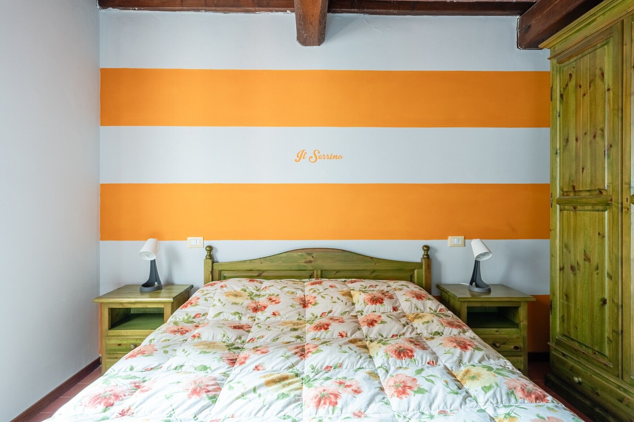 A bedroom with a bed, two bedside tables, a wooden headboard, and a wardrobe.