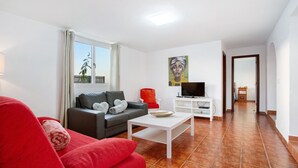 Una sala de estar con un sofá, una mesa de centro, un mueble para televisor y un cuadro en la pared.