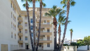 A multi-story building with balconies, palm trees, and a gated entrance. - Apartment 'Casa Vacanze Colopi' with Private Garden (Gallipoli)