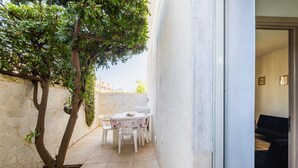 A small patio with a table and chairs, a tree, and a stone wall. - Apartment 'Casa Vacanze Colopi' with Private Garden (Gallipoli)
