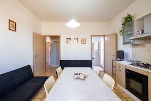 Et moderne køkken med spisebord, stole, sofa og fjernsyn.
