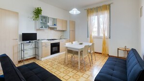 A compact living space with a kitchenette, a dining area, and a sofa. - Apartment 'Casa Vacanze Colopi' with Private Garden (Gallipoli)