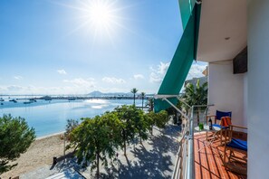 A balcony with a view of a marina, a beach, and a clear sky.