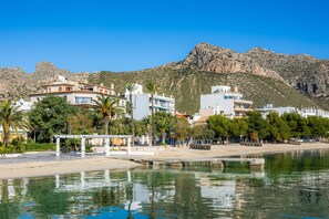 A coastal town with buildings, a beach, and mountains in the background. - Apartment 'Tonia' with Sea View, Wi-Fi and Air Conditioning (Puerto Pollensa)