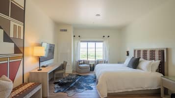 Habitación de hotel con cama, escritorio, silla, televisor y vista al exterior.
