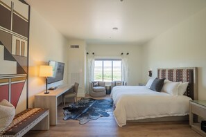 A hotel room with a bed, desk, chair, TV, and a view of the outdoors. - Taawaki Inn - Cottonwood. (Clarkdale)