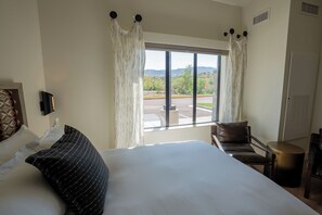 A hotel room with a large bed, a chair, a small table, and a TV. - Taawaki Inn - Cottonwood. (Clarkdale)