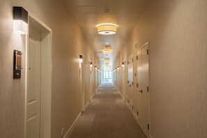 A hotel hallway with doors on both sides, overhead lighting, and a carpeted floor. - Taawaki Inn - Cottonwood. (Clarkdale)
