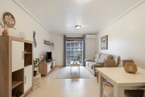 Ein modernes Wohnzimmer mit Sofa, Fernseher und einem Essbereich mit Tisch und Stühlen.