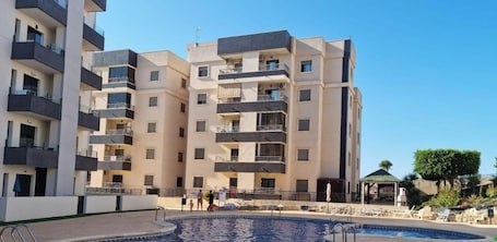 A multi-story hotel with balconies, a swimming pool, and a small outdoor seating area.. Apartment 'Carpediem in Spanje' with Lake View, Shared Pool and Wi-Fi