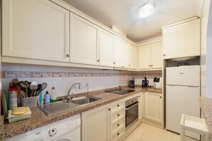 A kitchen with white cabinets, a granite countertop, a dishwasher, an oven, and a refrigerator. - Apartment 'Carpediem in Spanje' with Lake View, Shared Pool and Wi-Fi (San Miguel de Salinas)