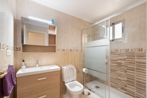 Une salle de bain moderne équipée d’une douche, de toilettes et d’un meuble-lavabo.