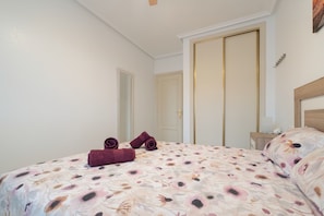 A bedroom with a bed, a nightstand, a mirror, and a door.