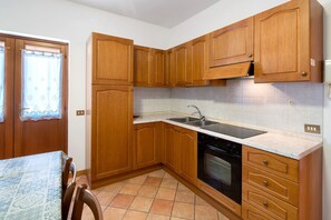 Une cuisine avec des meubles de rangement en bois, un évier, un four et une table à manger avec des chaises.