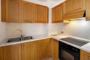 Een koelkast, een oven, een kookplaat, kookgerei, borden en bestek