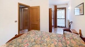 A bedroom with a bed, wooden wardrobe, and a chair. - Apartment 'Residence Malibu Appartamento 9' with Mountain View and Wi-Fi (Falcade)