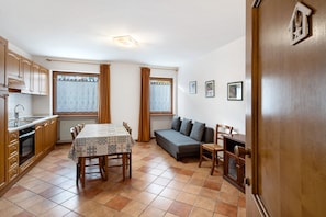 A compact kitchen with a dining table, a sofa, and a small cabinet.