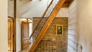 Een trap met een houten leuning en een metalen balustrade, leidend naar een kamer met een bakstenen muur en een ingelijste foto.