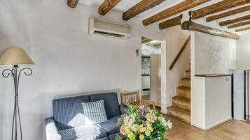 A living room with a striped sofa, a floor lamp, a floral arrangement, and a staircase leading to an upper level.