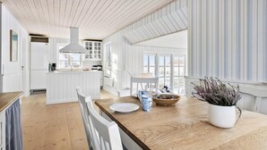 A modern kitchen with white cabinetry, a wooden countertop, and a large window providing natural light. - Lovely home in Hjørring with sauna (Hjørring)