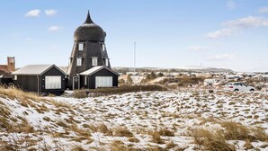 A unique black-roofed building with a conical tower, surrounded by a snowy landscape and a small village in the background. - Lovely home in Hjørring with sauna (Hjørring)