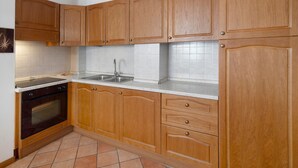 Eine Küche mit Holzausstattung, einer Edelstahl-Spüle und einem schwarzen Backofen.