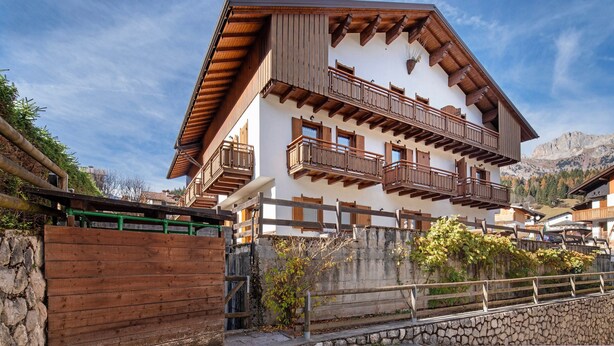 Ein mehrstöckiges Chalet mit Holzbalkonen, Steinwänden und einer Bergkulisse.