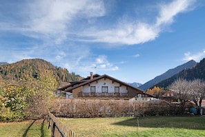 Une grande maison à deux étages dotée d’un balcon, entourée d’une pelouse bien entretenue et d’une clôture en bois.