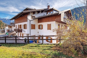 Un chalet traditionnel doté d’un balcon en bois, avec une vue sur les montagnes et un drapeau.
