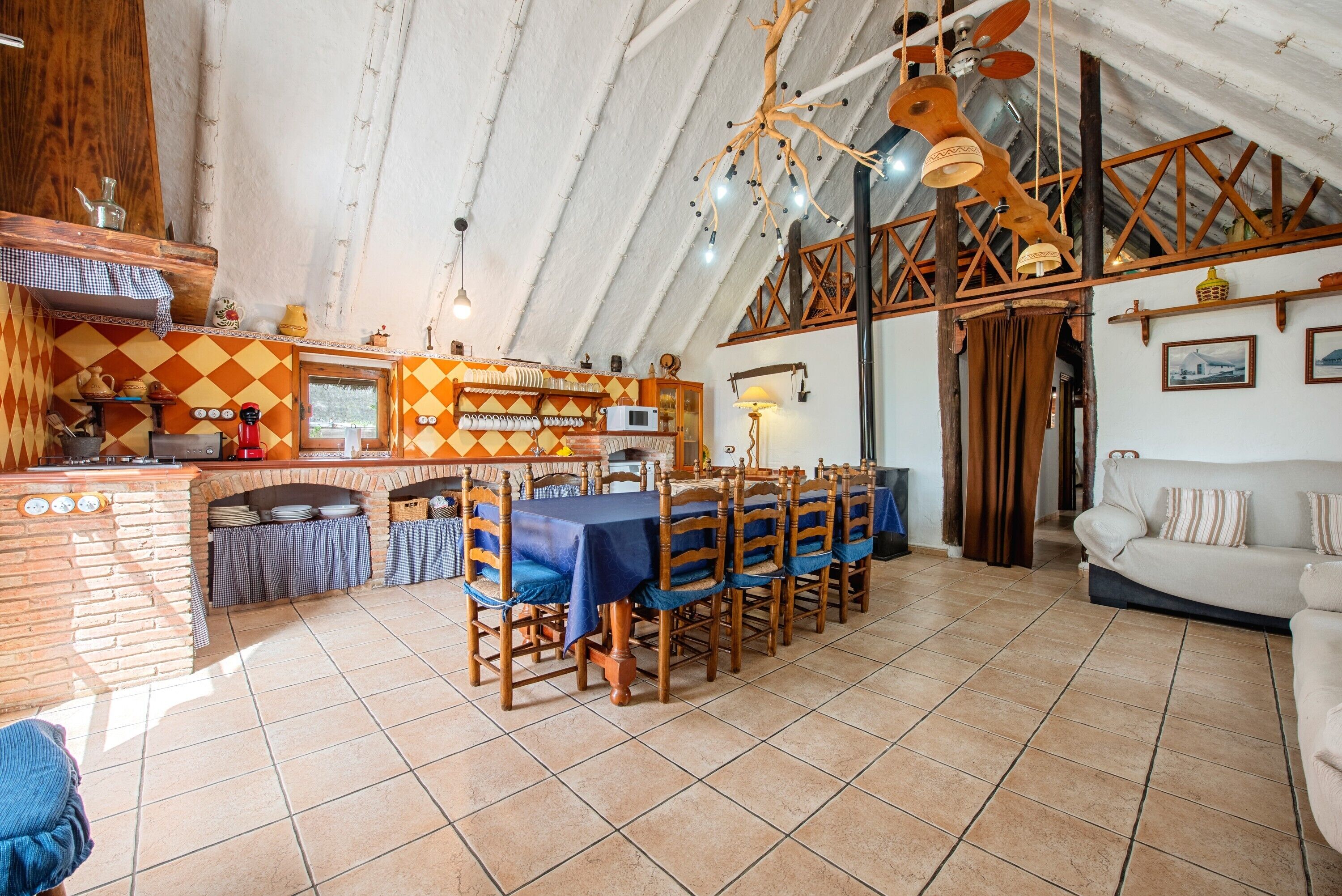 A rustic kitchen with a brick oven, wooden chairs, and a dining table.