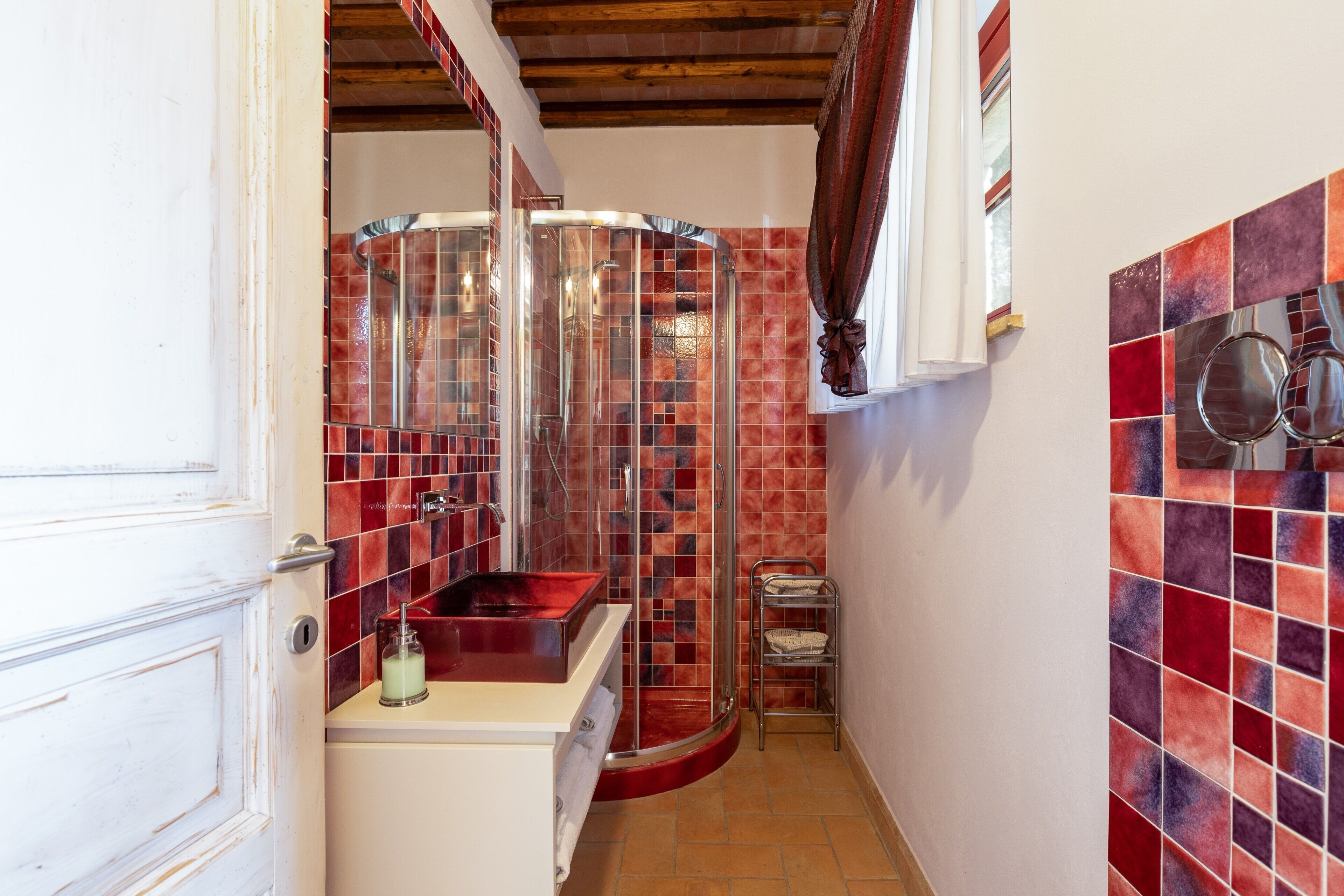 Un baño con ducha, lavamanos y un perchero para toallas.