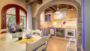 Una cocina con techo de ladrillo abovedado, una mesa de comedor con sillas y un taburete pequeño.