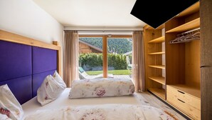 Een slaapkamer met een bed, een houten garderobe en uitzicht op een tuin.