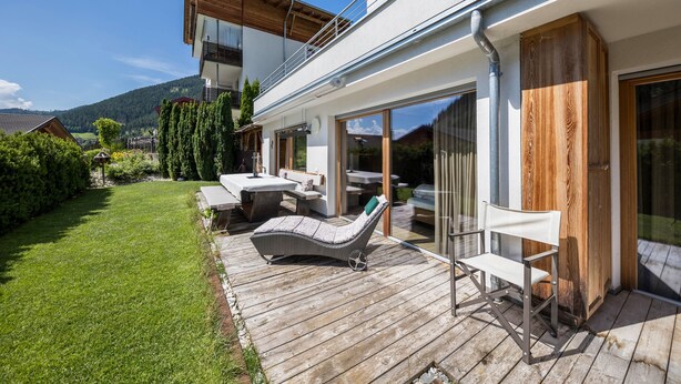 Een modern huis met terras, buitenmeubilair en uitzicht op het omliggende landschap.
