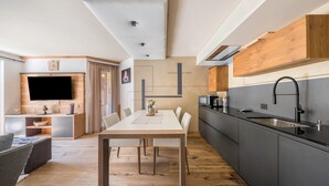 Een moderne keuken met een eethoek, houten vloeren en een flatscreen televisie.