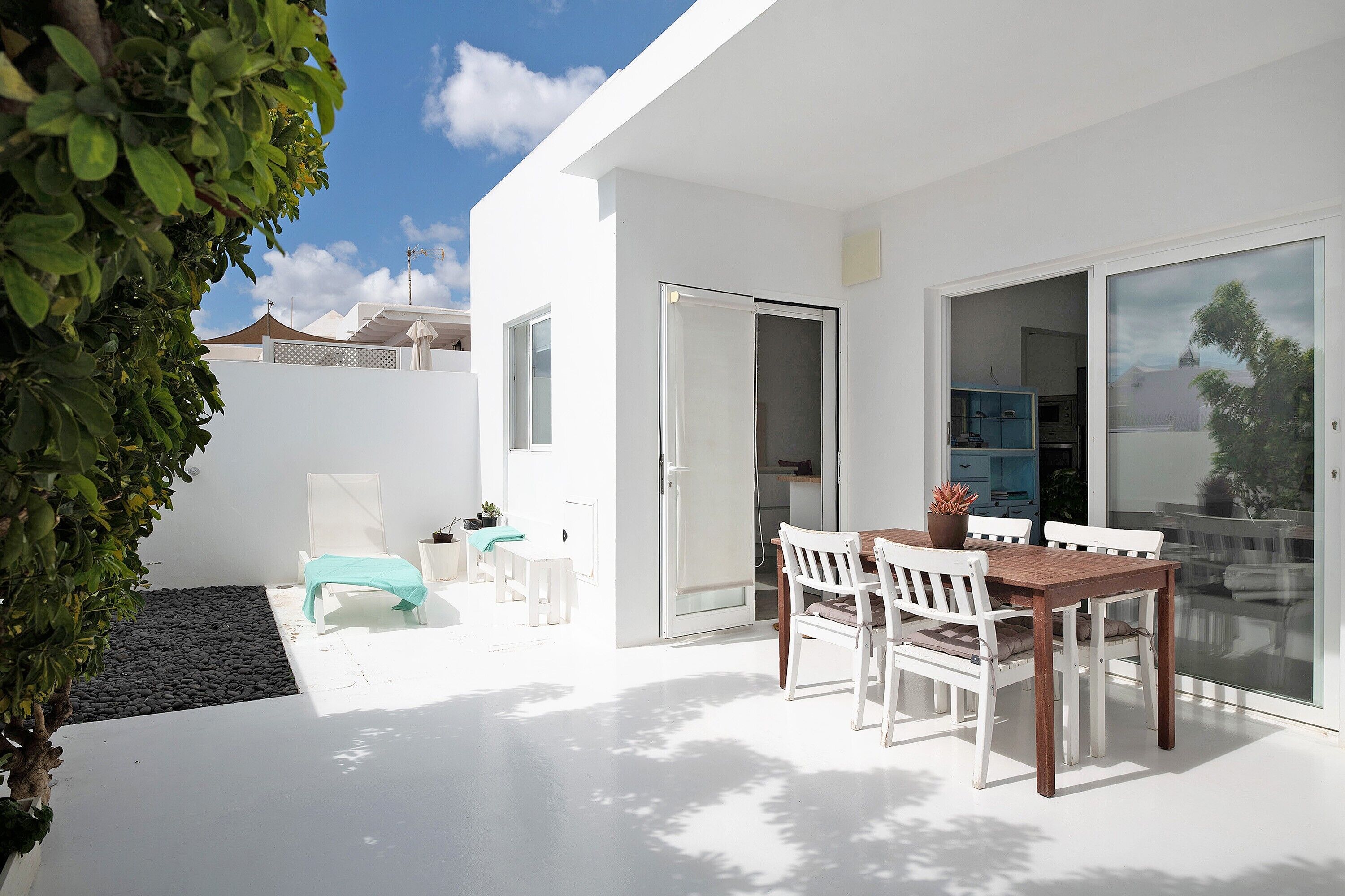 Une terrasse moderne avec une table et des chaises, un petit coin salon et une porte vitrée donnant sur un espace extérieur abrité.