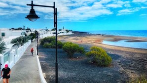 Un paseo marítimo con un farol, un ciclista y una playa al fondo.