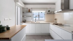 Una cocina moderna con armarios blancos, encimera de madera y ventana sobre el fregadero.