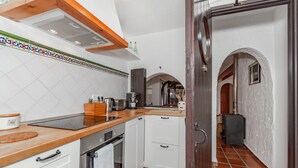 A compact kitchen with white cabinets, a wooden countertop, and a tiled backsplash. - Charming Holiday Home with Sea Views, Private Pool and Wi-Fi (Binibèquer)